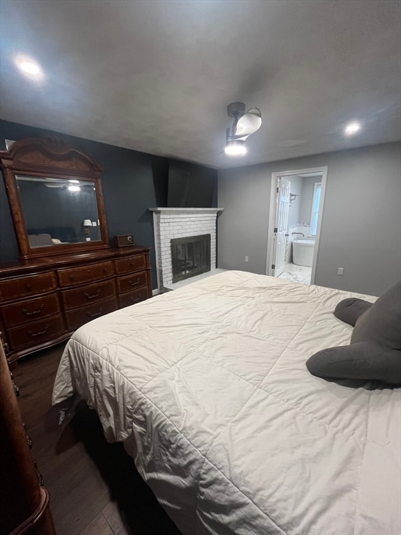 bedroom with a fireplace, wood-type flooring, and connected bathroom