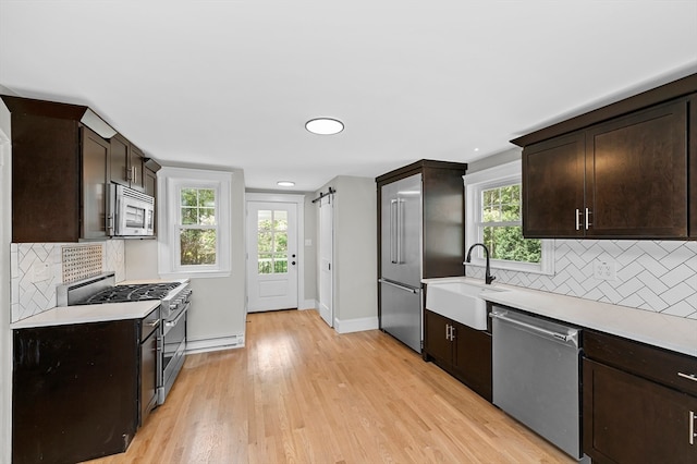 kitchen with light wood-type flooring, appliances with stainless steel finishes, a wealth of natural light, and sink