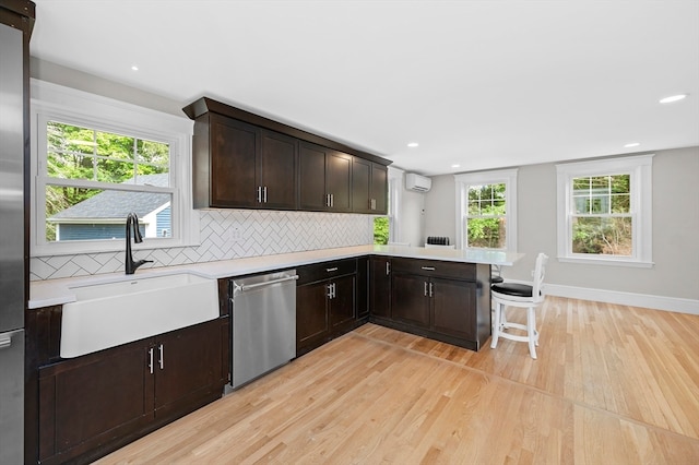 kitchen with dishwasher, light hardwood / wood-style flooring, kitchen peninsula, sink, and an AC wall unit