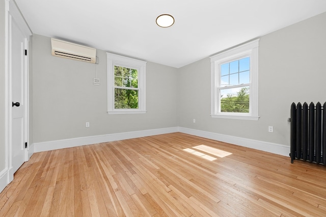 unfurnished room featuring light hardwood / wood-style floors, radiator heating unit, and an AC wall unit