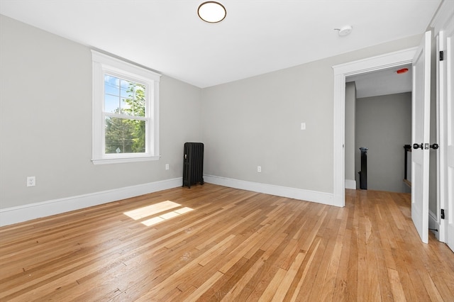 unfurnished room with radiator and light wood-type flooring