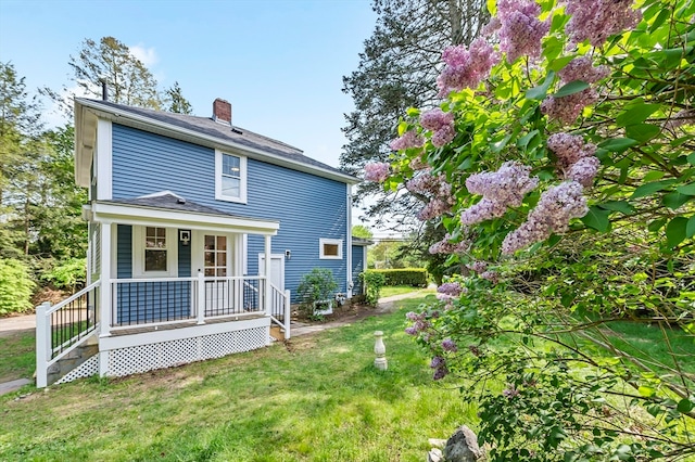 back of property featuring a lawn and a porch