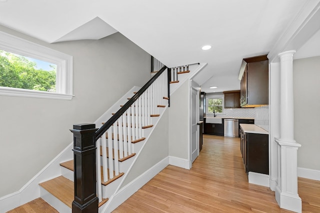 staircase featuring hardwood / wood-style floors, sink, and decorative columns