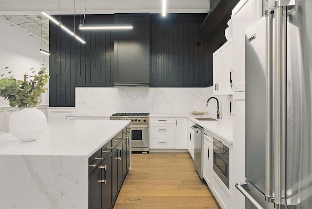 147 Sherman St Unit 201, Cambridge, MA 02140 - kitchen featuring high end appliances, a sink, white cabinets, light wood finished floors, and backsplash
