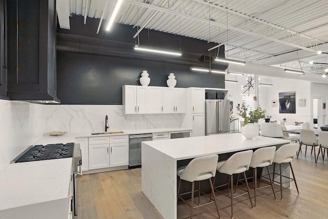 147 Sherman St Unit 201, Cambridge, MA 02140 - kitchen with appliances with stainless steel finishes, a sink, white cabinetry, tasteful backsplash, and light countertops