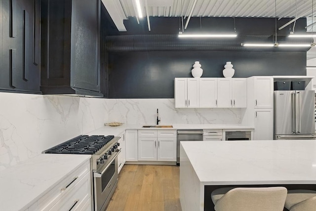 147 Sherman St Unit 201, Cambridge, MA 02140 - kitchen featuring high quality appliances, a sink, light wood finished floors, white cabinetry, and backsplash
