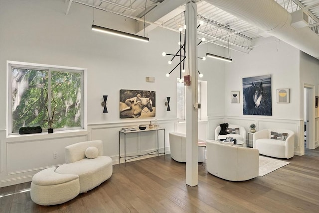 147 Sherman St Unit 201, Cambridge, MA 02140 - living room with a towering ceiling, wood finished floors, a decorative wall, and wainscoting