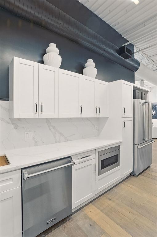 147 Sherman St Unit 201, Cambridge, MA 02140 - kitchen with stainless steel appliances, white cabinets, backsplash, and a towering ceiling