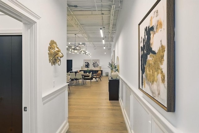 147 Sherman St Unit 201, Cambridge, MA 02140 - corridor with a chandelier, light wood-style floors, wainscoting, a decorative wall, and track lighting