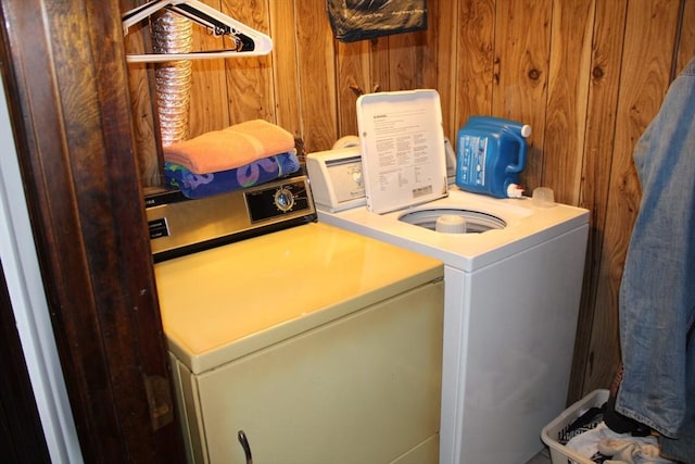 laundry room with laundry area, wooden walls, and washer and dryer