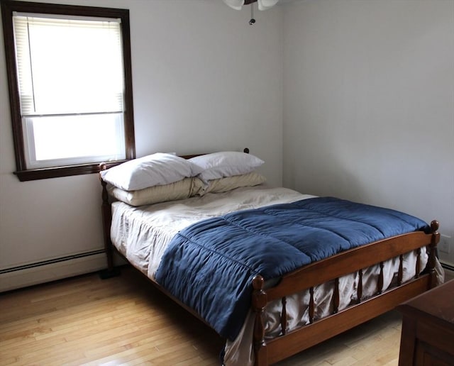 bedroom with baseboard heating and light wood-type flooring