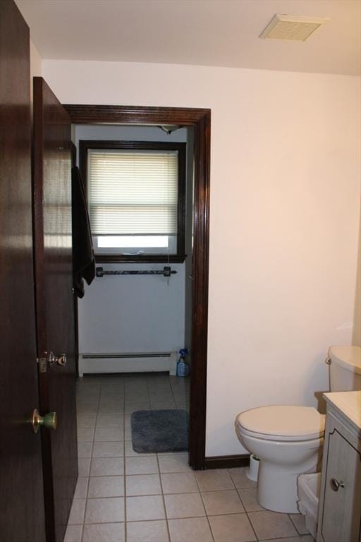 half bathroom with vanity, tile patterned floors, baseboard heating, and toilet