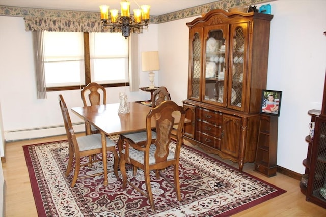 dining room featuring an inviting chandelier, baseboards, light wood finished floors, and a baseboard heating unit
