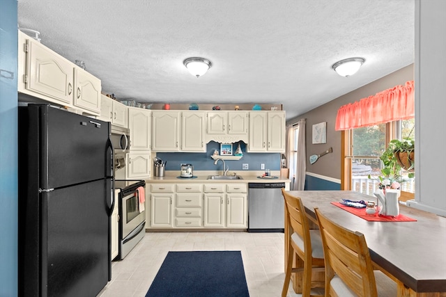 kitchen featuring cream cabinets, stainless steel appliances, a textured ceiling, light tile patterned floors, and sink