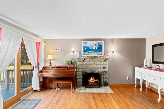 living area with a brick fireplace, hardwood / wood-style floors, and a textured ceiling