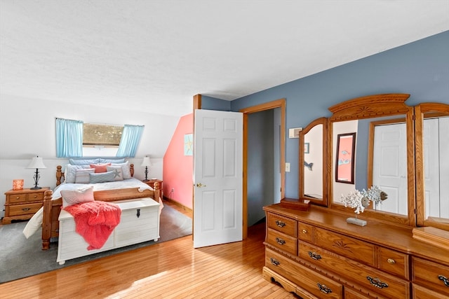 bedroom with vaulted ceiling and light hardwood / wood-style flooring