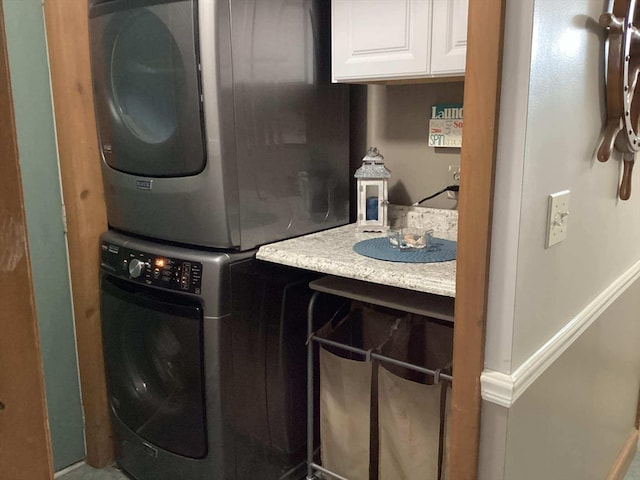 clothes washing area featuring cabinets and stacked washer / dryer