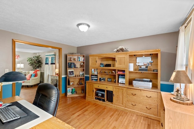 office with light wood-type flooring and a textured ceiling