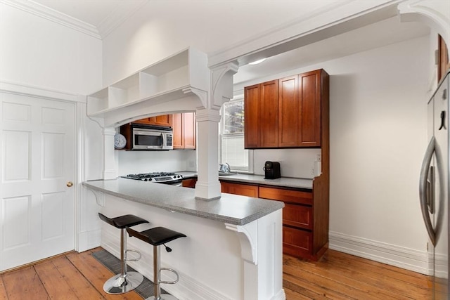 6 Brigham St Unit 1, Boston, MA 02128 - kitchen featuring appliances with stainless steel finishes, decorative columns, light wood finished floors, ornamental molding, and brown cabinetry