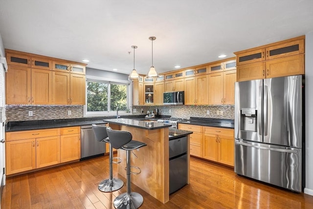 kitchen with stainless steel appliances, wood-type flooring, glass insert cabinets, and tasteful backsplash