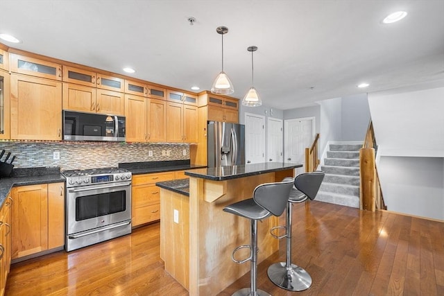 kitchen with stainless steel appliances, backsplash, hardwood / wood-style floors, and a center island