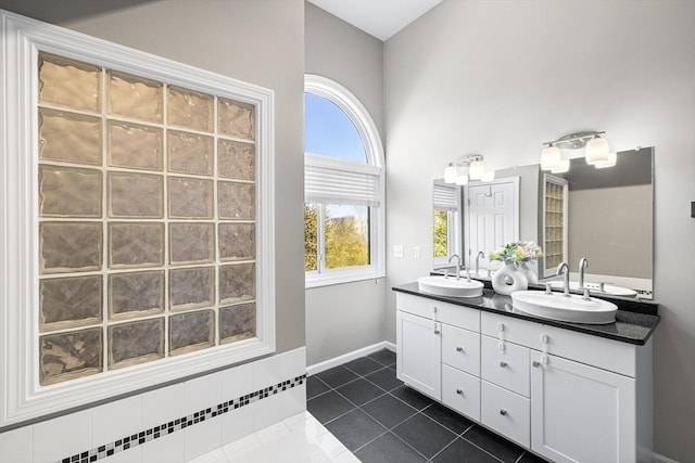 full bath featuring tile patterned flooring, double vanity, baseboards, and a sink