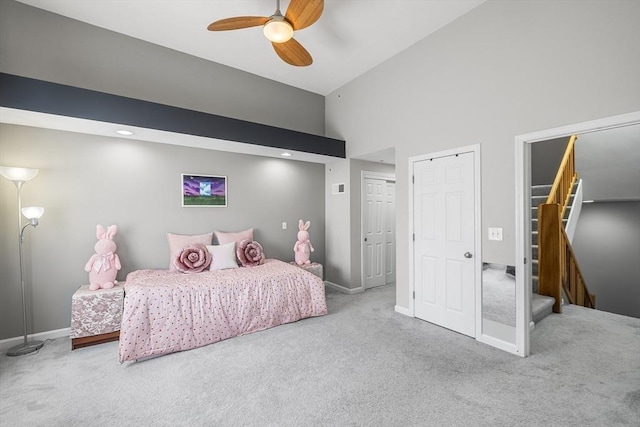 carpeted bedroom with ceiling fan, baseboards, and high vaulted ceiling