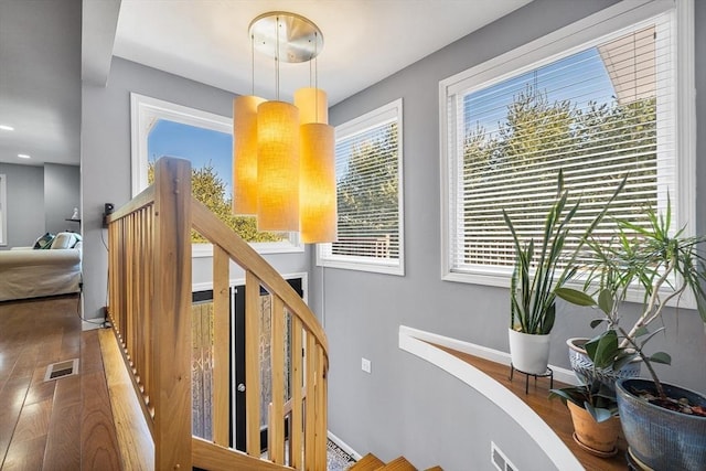 stairs with hardwood / wood-style floors, baseboards, and visible vents