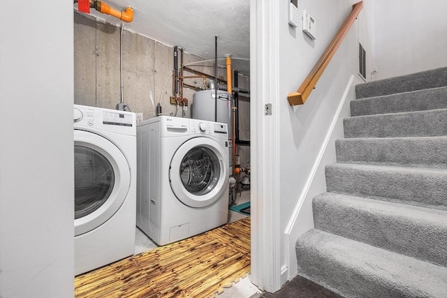 laundry room with visible vents, water heater, laundry area, wood finished floors, and separate washer and dryer