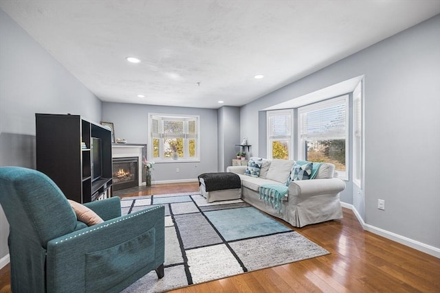 living area with a fireplace with flush hearth, recessed lighting, baseboards, and wood finished floors