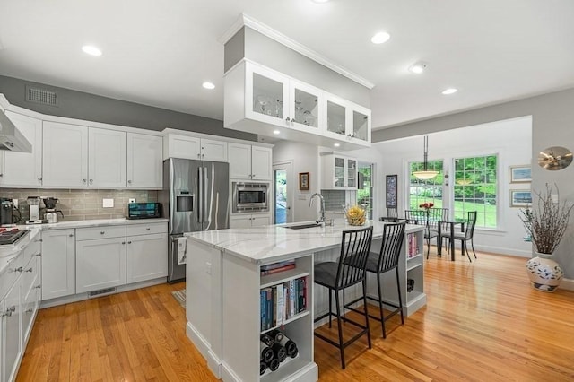 14 Parsons Hill Rd, Wenham, MA 01984 - kitchen with stainless steel appliances, a sink, light wood finished floors, white cabinets, and a center island with sink