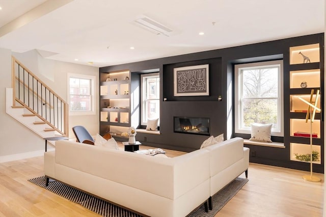 living room with built in features and light hardwood / wood-style floors