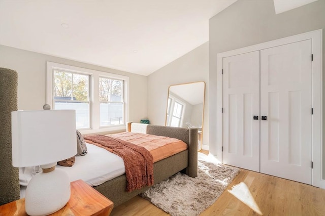 bedroom with a closet, lofted ceiling, and light hardwood / wood-style flooring