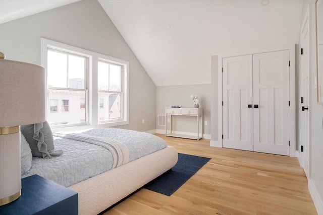 bedroom featuring hardwood / wood-style floors, vaulted ceiling, and a closet