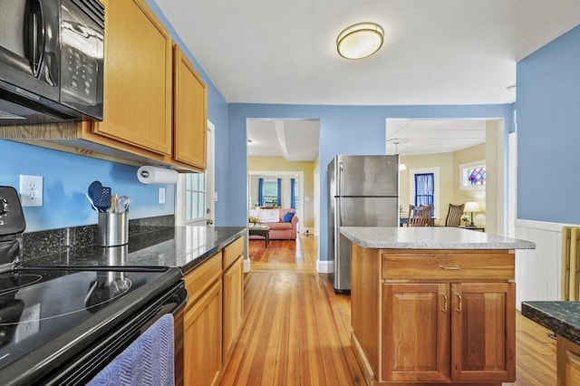 23 Starbird St, Lowell, MA 01854 - kitchen featuring black appliances, a wainscoted wall, light wood-style flooring, and brown cabinets