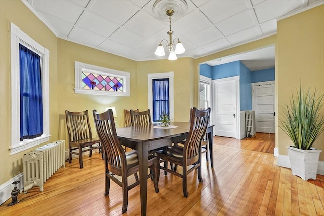 23 Starbird St, Lowell, MA 01854 - dining room with radiator heating unit, light wood-style floors, a chandelier, ornamental molding, and plenty of natural light