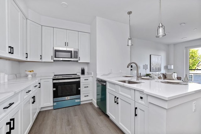 kitchen featuring pendant lighting, sink, stainless steel appliances, white cabinets, and kitchen peninsula