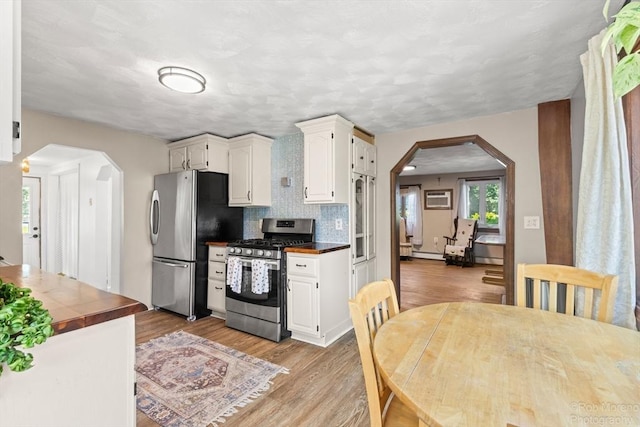 91 Bartholomew St, Peabody, MA 01960 - kitchen with appliances with stainless steel finishes, arched walkways, light wood-style flooring, and white cabinetry