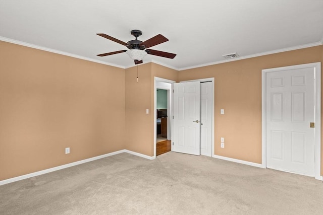unfurnished bedroom with baseboards, light colored carpet, crown molding, a closet, and ceiling fan
