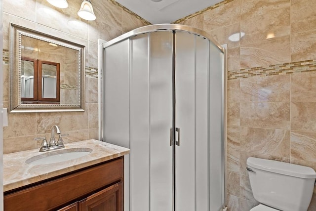 bathroom with tile walls, a stall shower, toilet, vanity, and tasteful backsplash