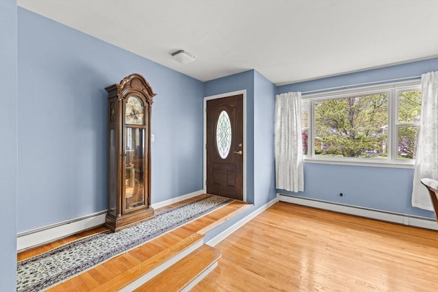 foyer entrance featuring wood finished floors, baseboard heating, and baseboards