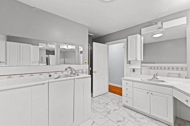 bathroom featuring marble finish floors, vanity, and baseboards