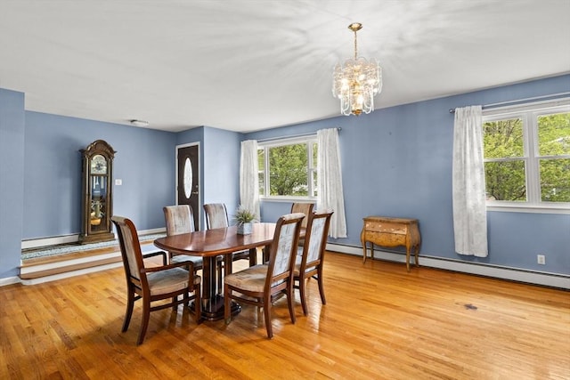 dining room with light wood-type flooring, baseboard heating, and a chandelier