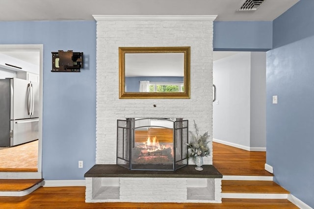 detailed view of freestanding refrigerator, wood finished floors, and baseboards