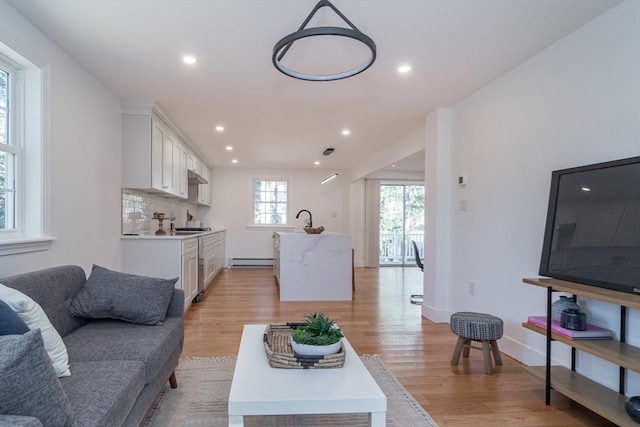 living room with recessed lighting, baseboards, baseboard heating, and light wood-style flooring