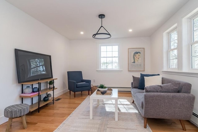 living area with a baseboard heating unit, recessed lighting, light wood-style floors, and baseboards