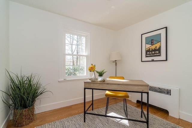 office area featuring baseboards, wood finished floors, and radiator heating unit