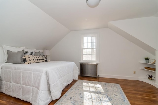 bedroom with baseboards, radiator, wood finished floors, and vaulted ceiling