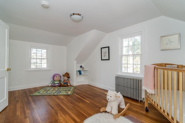 game room with hardwood / wood-style floors, vaulted ceiling, radiator, and baseboards