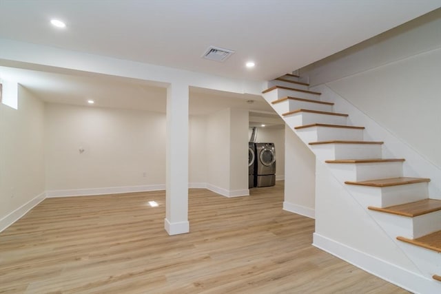 finished below grade area with wood finished floors, visible vents, washing machine and clothes dryer, recessed lighting, and stairs